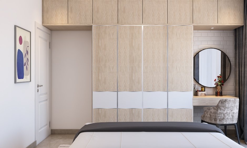 A floor-to-ceiling wardrobe in the wooden finish in 1bhk interior brings a clean look and ample storage space