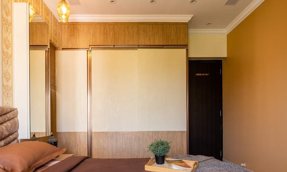 Guest bedroom design by DC interior designer in Kandivali, featuring wood and white sliding wardrobe.