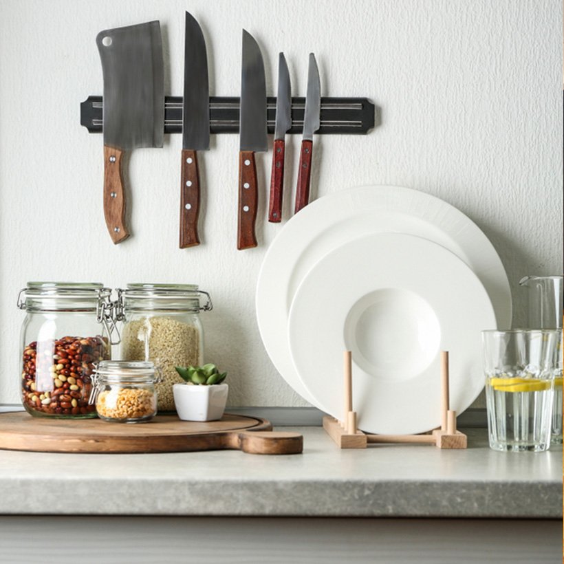 Kitchen organizer rack and a countertop to place the cutleries on the countertop and jars filled with pulses and a knife organiser hanging on the wall which tells us how to organise a kitchen