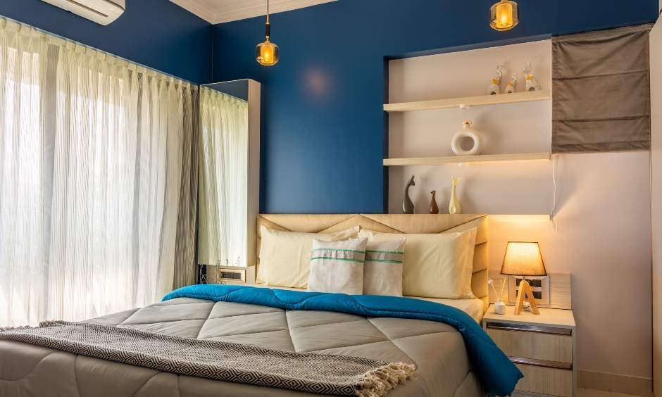 Master bedroom interior in Kandivali West with floating shelves, side table, and compact vanity.