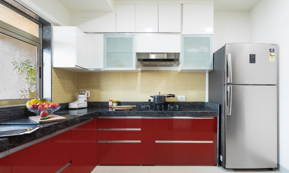 A modular kitchen in white and red with overhead and base cabinets designed by best residential interior designers in mumbai